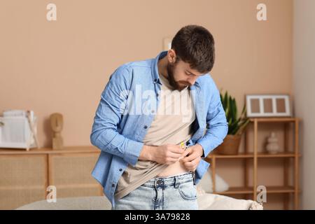 Diabetic young man giving himself insulin injection in kitchen Stock ...