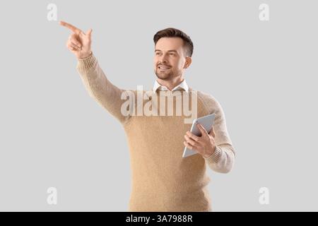 Young businessman with tablet computer using virtual screen on light background Stock Photo