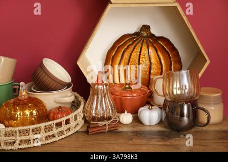 Beautiful autumn decor and dishes on wooden table near color wall Stock Photo