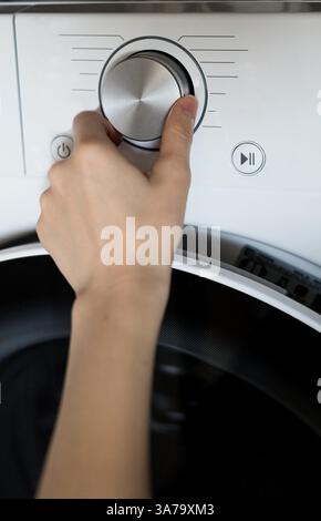woman's hand adjusts the washing program in the washing machine Stock Photo