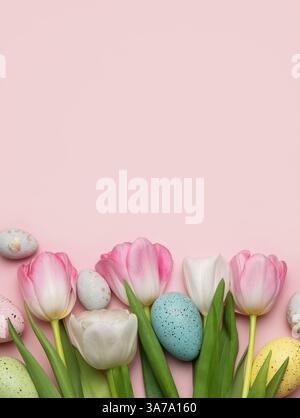 Colorful easter eggs and tulips arranged on a pink background create a cheerful spring border Stock Photo