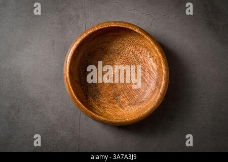 Top view of empty wooden nuts bowl on dark grey stone table Stock Photo