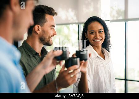 Happy creative diverse colleagues having fun while talking and drinking coffee, tea in working break Stock Photo