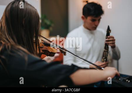 Two musicians practicing violin and clarinet together in a cozy room. Stock Photo