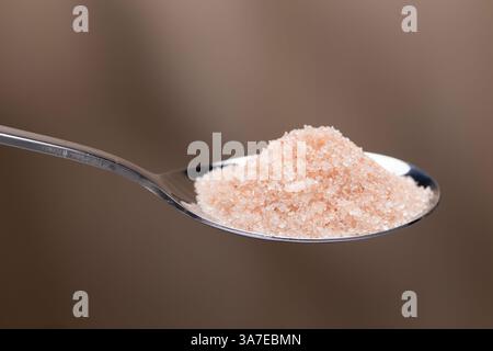 This close-up shot captures the delicate texture of Himalayan Pink Salt piled on a stainless steel spoon, highlighting its unique color. Stock Photo