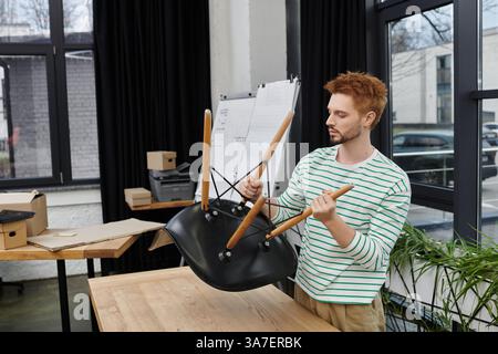 A man expertly assembles a chair in a modern office while getting ready to relocate. Stock Photo