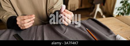 A young woman skillfully threads a needle in a cozy, inspiring crafting space. Stock Photo