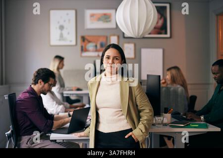 Portrait of confident female business professional standing with hand in pocket at office Stock Photo