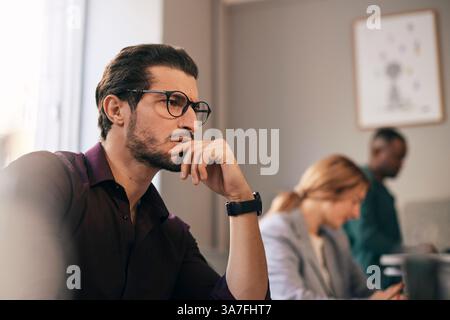 Thoughtful young businessman with hand on chin working in office Stock Photo