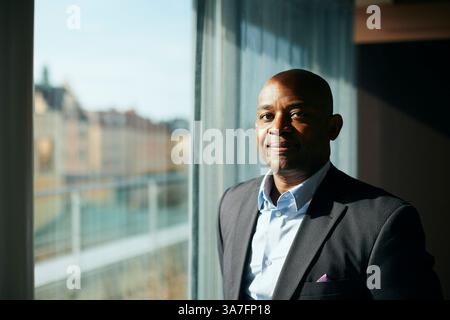 Portrait of smiling bald male entrepreneur near window at office Stock Photo