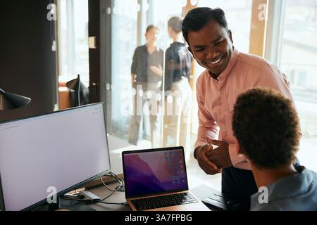 Happy male entrepreneur talking with female coworker in office Stock Photo