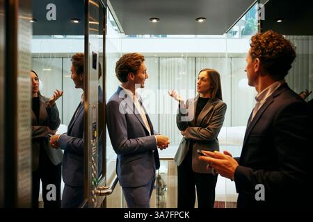 Female entrepreneur talking with male coworker in elevator at office Stock Photo