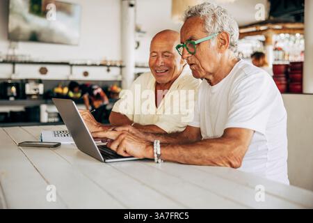 Senior man using laptop while sitting at table in vacation rental Stock Photo