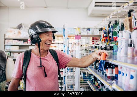 Happy senior man wearing helmet shopping at store Stock Photo