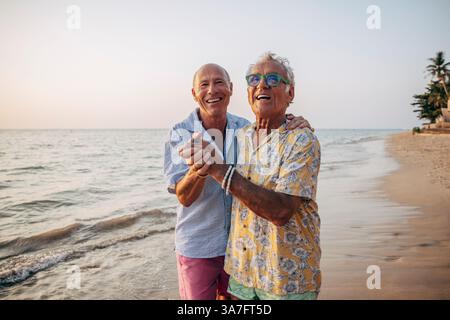Happy elderly gay couple dancing on beach at Ko Lanta island Stock Photo