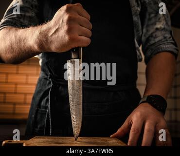 Chief Holding A Big Knife On A Cut Board In The Kitchen Stock Photo
