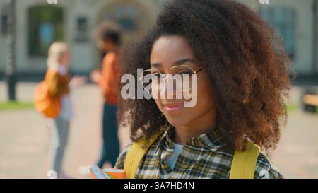 Portrait happy student positive friendly African American woman female girl smiling at camera holding books study near university campus college Stock Photo