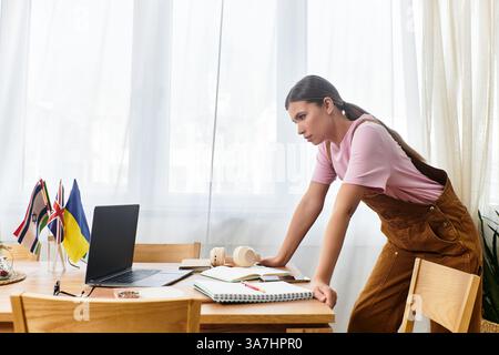 Focused young woman leans over her desk, deep in thought while studying with flags nearby. Stock Photo