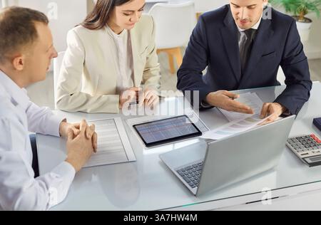 Business people working in office looking through financial documents analyzing company finances. Stock Photo