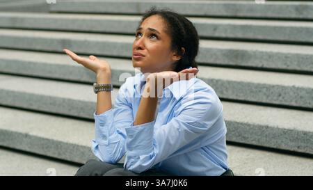 Depressed stressed African American businesswoman talking to God heaven upset business woman girl female employer suffering failure job lost in city Stock Photo