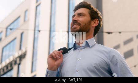 Close up Caucasian smiling stylish relaxed confident middle-aged businessman business man male guy entrepreneur in sunny sun light city exhale put Stock Photo