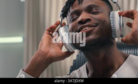 Portrait emotional happy carefree satisfied relaxed ethnic man African American male guy indoors in white futuristic studio relaxing freedom smiling Stock Photo