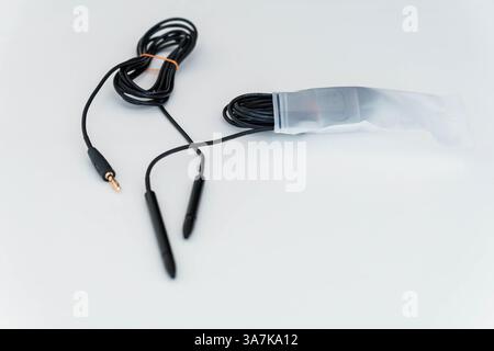 Isolated Audio Cable with Double Plug Connector Partially Stored in Plastic Packaging on White Surface. Stock Photo