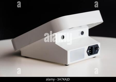 Close-up Rear View of Modern White Electronic Device on a Table Against Black Background. Stock Photo