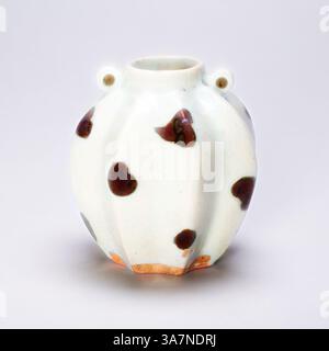 A small, round vase with a fluted design, featuring a pale white surface adorned with irregular brown spots. Two small circular handles are positioned near the top, adding a decorative touch to its charming appearance., Classic art with a modern twist reimagined by Artotop, Lobed Jar in Form of Balambing (Philippine Island Star Fruit), Yuan dynasty (1279–1368), first half of 14th century, China, Qingbai ware, glazed porcelain with iron spots, H. 6.9 cm (2 3/4 in.), diam. 6.5 cm (2 9/16 in.) Stock Photo