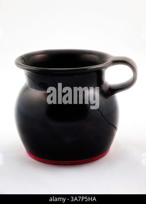 A traditional clay pot features a rounded body and a sturdy handle, adorned with a subtle red detail at the base. The surface exhibits a smooth finish, highlighting its craftsmanship and timeless design., Classic art with a modern twist reimagined by Artotop, Mug, about 460 BC, Greek, Athens, Greece, terracotta, decorated in the black-glaze technique Stock Photo