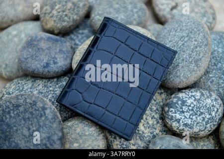 A black leather wallet for men, placed on stones Stock Photo