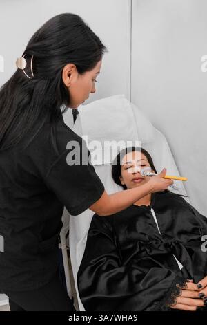 Professional makeup artist applying a mask to prepare the skin before applying makeup. Stock Photo