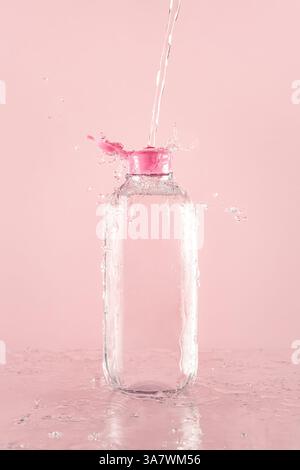 Cleansing water fluid over transparent plastic bottle with splashes and drops on smooth wet surface Stock Photo