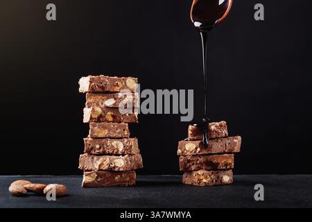 Pieces of chocolate bars placed in piles on table with almonds and poured with sweet sauce Stock Photo