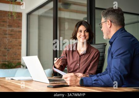 Two executives team working on laptop discussing documents at office meeting. Stock Photo
