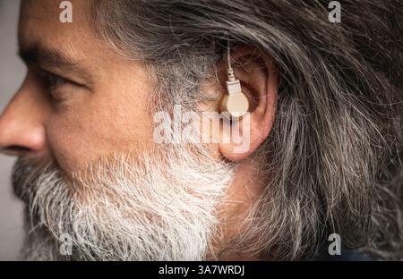 Hearing aid in the ear of a middle-aged man Stock Photo