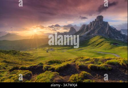 Lush green valley, beautiful alpine mountains during colorful sunset in summer.  Passo Giau, Dolomites, Italy. Landscape with green meadows, road, hig Stock Photo