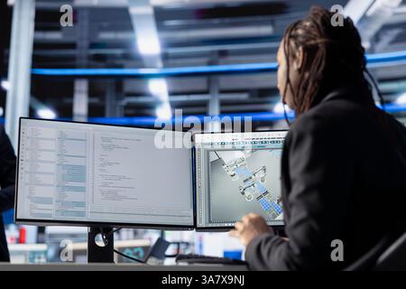 Photovoltaics factory software developer coding program monitoring system performance. African american woman in solar panels plant writing code, tracking energy production and efficiency Stock Photo