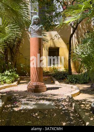 Ajaccio, Corsica, France July 8, 2024: Bonaparte museum garden in Rue Saint Charles, a narrow alley. Bust statue of Napoleon as a kid placed on a pill Stock Photo