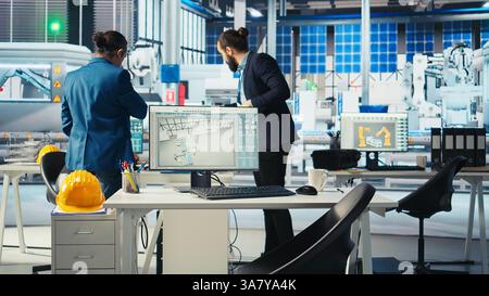 Photovoltaics factory manager working with solar engineering team to improve new system design and reliability. Solar panel manufacturing plant inspector providing feedback to employees Stock Photo