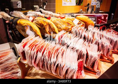 Lviv, Ukraine - March 25, 2025: Various cured ham legs and packaged sliced meat displayed for sale in a store. Stock Photo