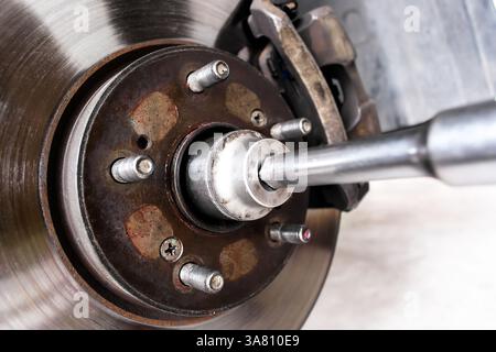 Close-up of removing a hub nut of front drive shaft or disc brake with mechanic tools to repair , Car repair concept Stock Photo