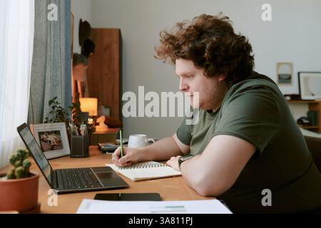 Man Working from Home Using Laptop on Wooden Desk Stock Photo