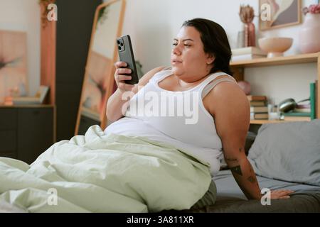 Woman Relaxing on Bed While Using Smartphone Stock Photo