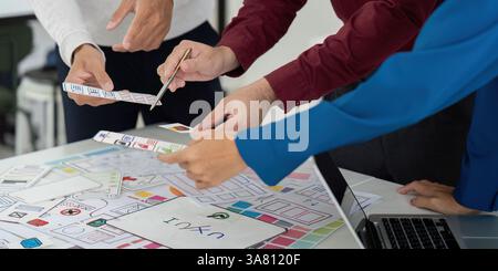 Collaboration and UX Design. Team members engaged in a collaborative UX design meeting, analyzing prototypes and sketching ideas together. Stock Photo