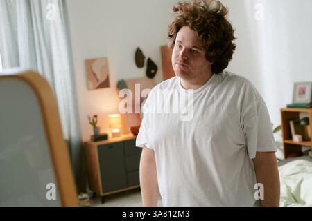 Portrait of Curly-Haired Man Standing in Cozy Bedroom Stock Photo