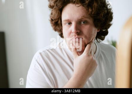 Portrait of Pensive Young Man Touching His Chin Stock Photo