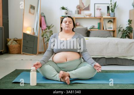 Pregnant Woman Meditating in Cozy Bedroom Setting Stock Photo