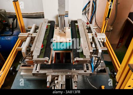 Innovative semi-automatic machine expertly wrapping rectangular boxes in a bustling packaging facility Stock Photo