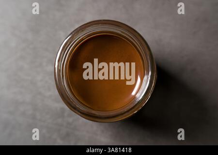 Top view of chocolate spread or nougat cream with hazelnuts in glass jar on dark background Stock Photo